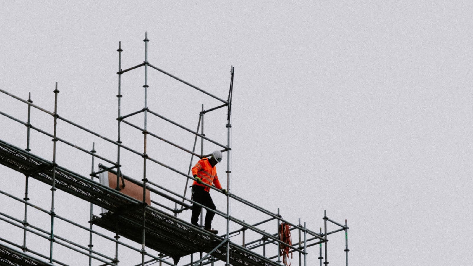 Ouvrier en gilet haute visibilité travaillant sur un échafaudage en hauteur.