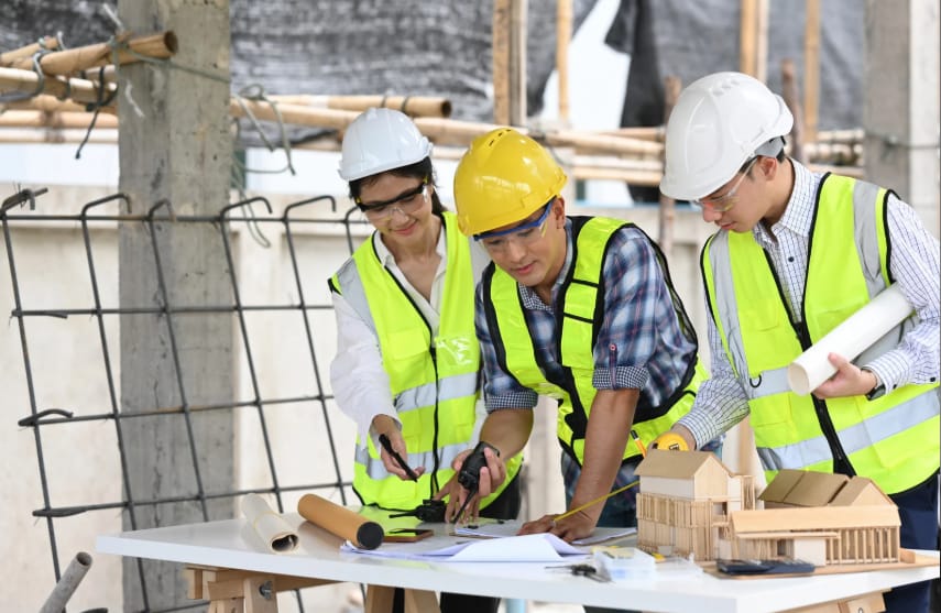 Deux ingénieurs en gilet haute visibilité examinant un bâtiment en structure sur un chantier.