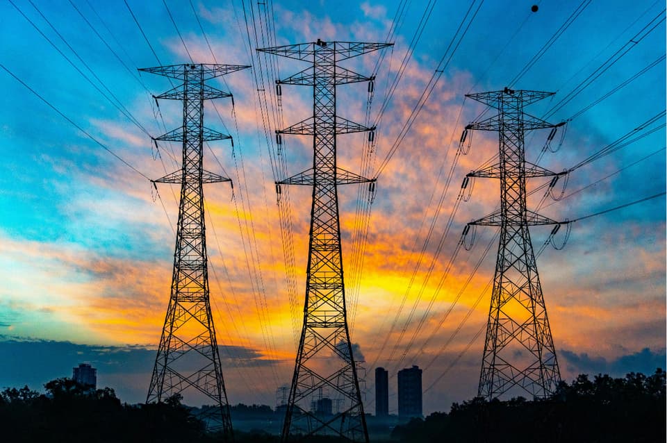 Barrage hydroélectrique, éolienne et panneaux solaires dans un paysage de vallée.