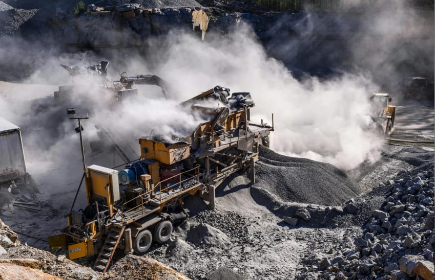 Excavatrice et tombereau de chantier dans une mine à ciel ouvert au lever du jour.